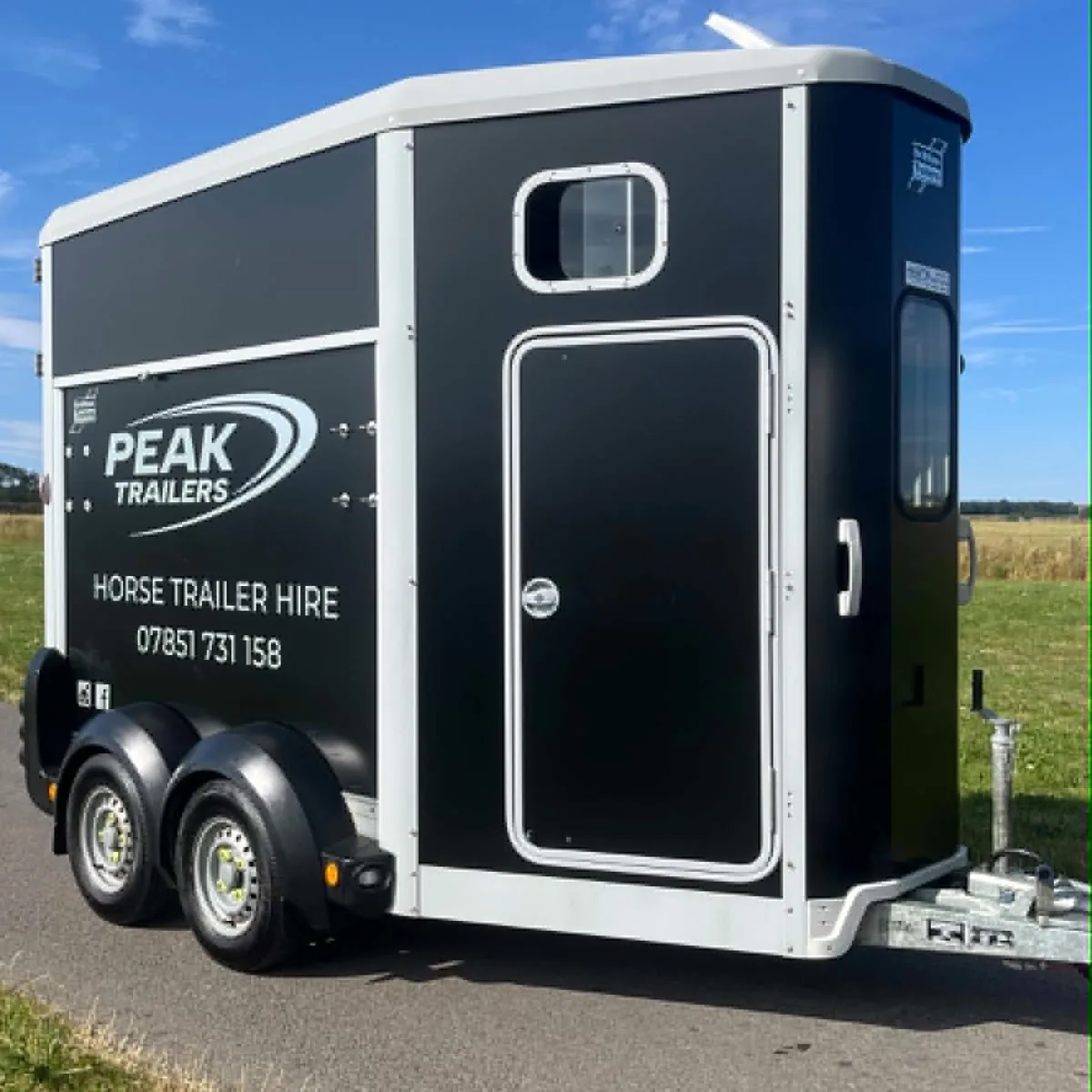 Black Ifor Williams HB506 horse trailer in Peak Trailers livery parked beside a field, available for hire