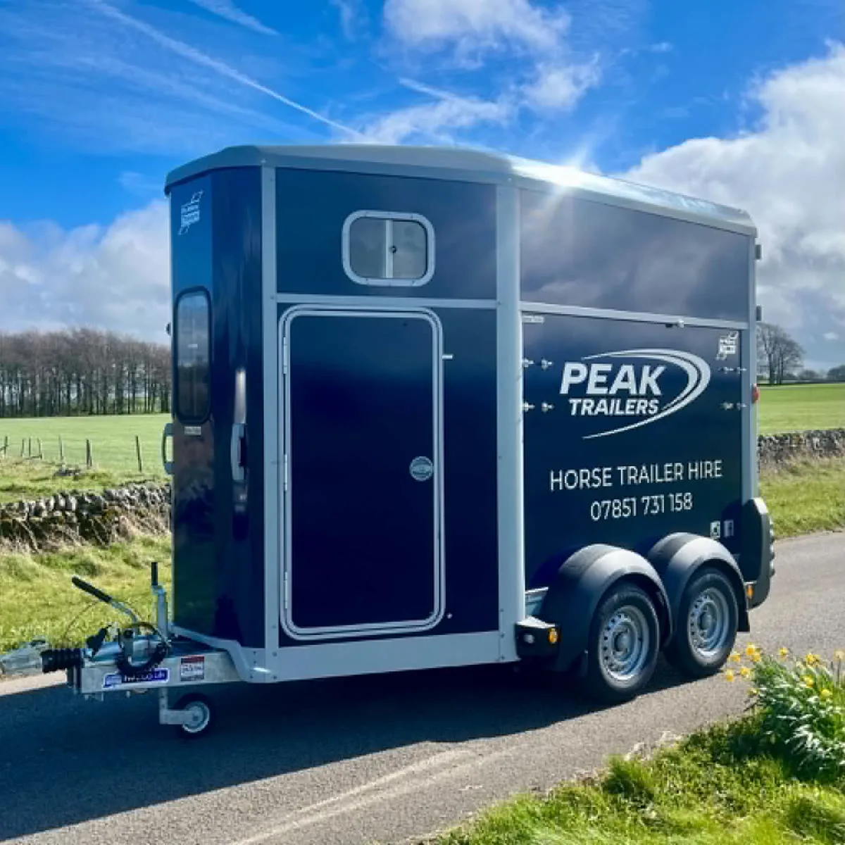 Blue Ifor Williams HB506 horse trailer in Peak Trailers livery on a country road, available for hire